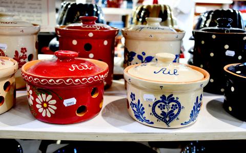 Decorated clay pots for storing garlic (foreground) and onions wait for buyers in the Ernewein-Haas pottery store in Soufflenheim, France, Nov. 8, 2021. In the background, baking molds for making traditional Alsatian gugelhupf cake are visible.