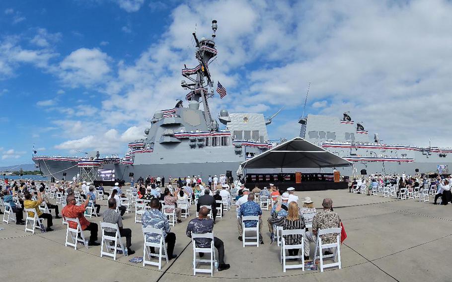 An audience of hundreds gather on a pier at Joint Base Pearl Harbor-Hickam, Hawaii, for the commissioning of the guided-missile destroyer USS Daniel Inouye, Wednesday, Dec. 8, 2021.