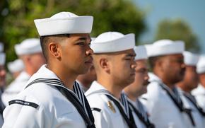 Uniformed sailors stand in formation.