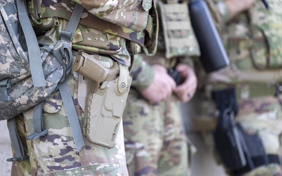 A closeup of a sidearm at a soldier’s hip.