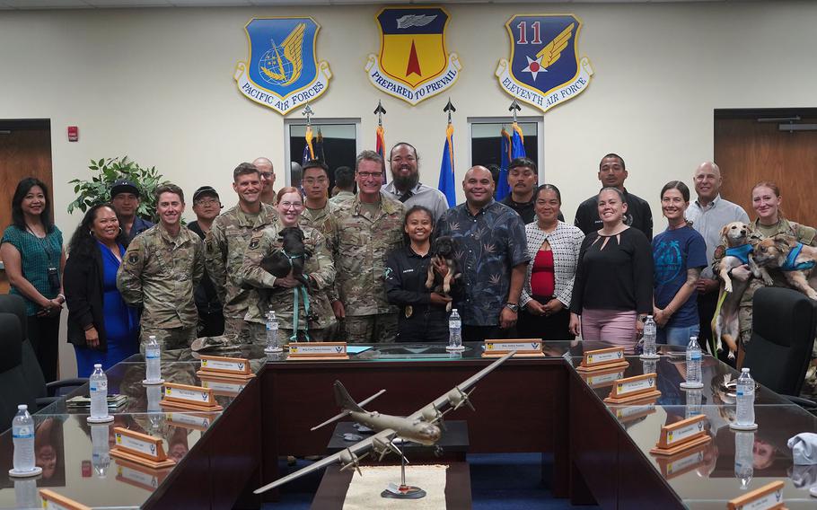 A group of U.S. military members and Guam government officials pose for a photo holding dogs.