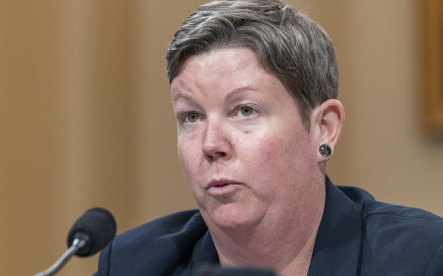 A woman with short hair sits in front of a microphone at a congressional hearing.