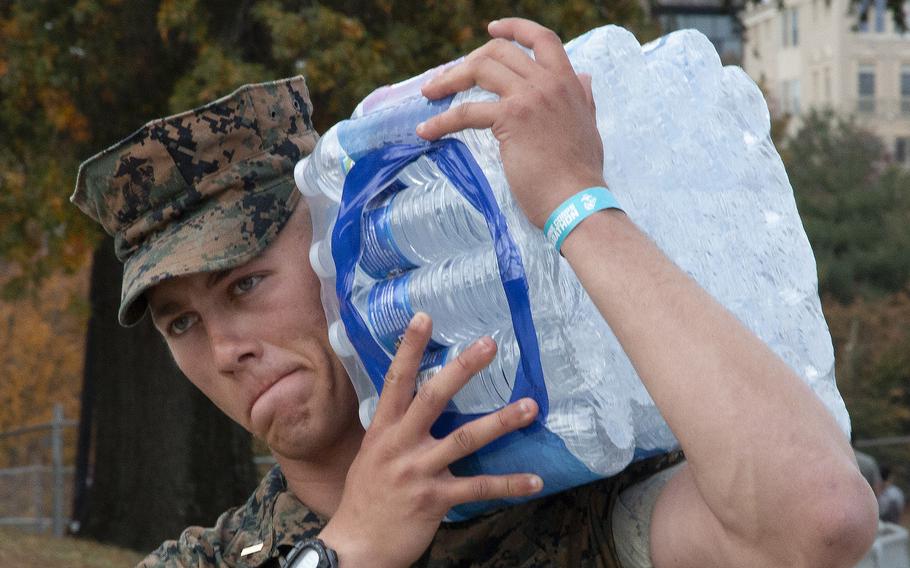 A Marine brings refreshments to thirsty runners at the finish line of the 48th Marine Corps Marathon on Sunday, Oct. 29, 2023, in Arlington, Va.