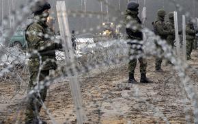 Guards and the military watching the start of work on the first part of some 180 kilometers (115 miles) of a 5.5 meter (18ft)-high metal wall intended to block migrants pushed by Belarus, in what the European Union calls a "hybrid attack," from crossing illegally into EU territory, in Tolcze, near Kuznica, Poland, on the Polish side of the border with Belarus on, Thursday, Jan. 27, 2022. (AP Photo/Czarek Sokolowski)