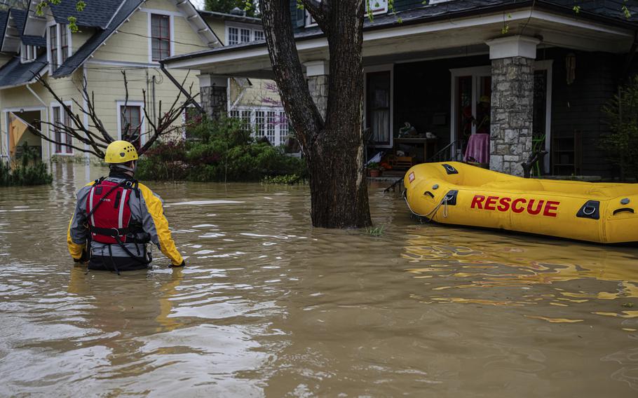 A firefighter walks through a flooded area near a house.