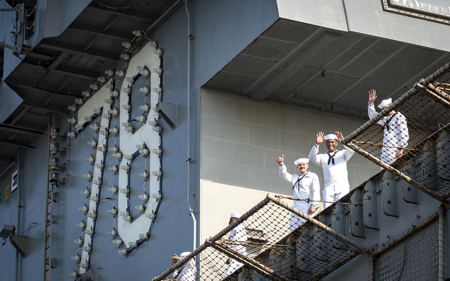 Sailors on a ship wave.