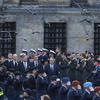 A group of service members in uniform on either side of a group of dignitaries.