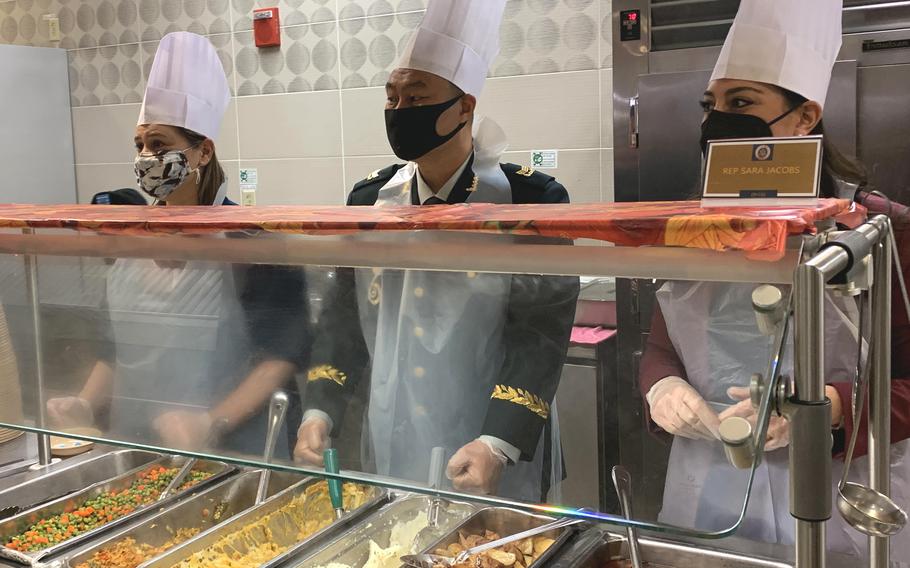 Reps. Elissa Slotkin of Michigan, left, and Sarah Jacobs of California, right, serve Thanksgiving meals with a South Korean service member at a dining facility at Camp Humphreys, South Korea, on Nov. 25, 2021.