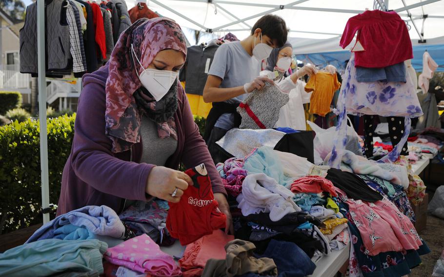 Zulfar Shaker, left, and other volunteers from the San Diego Afghan Refugees Aid Group sort through clothes during a distribution event to help afghan refugees on Sunday, Jan. 9, 2022. The volunteer event distributed clothing, food and toys to afghan refugees who recently came to the United States and are living in hotels. 