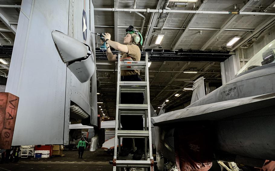 A sailor works on an F/A-18 Super Hornet in the hangar bay of the aircraft carrier USS Dwight D. Eisenhower on March 20, 2024. The carrier has launched about 100 flights daily since Dec. 31.
