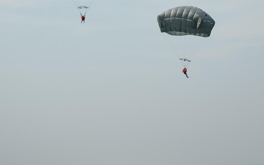 Two paratroopers descending above the water, with a boat floating nearby.