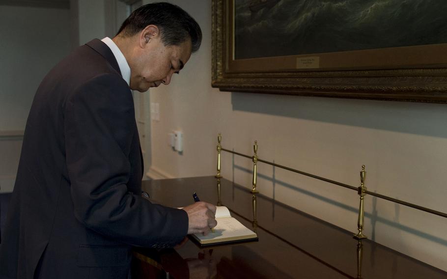 Foreign Minister of the People's Republic of China Wang Yi signs a guest book as he arrives for a meeting at the Pentagon in Arlington, Va., Oct. 1, 2014. 
