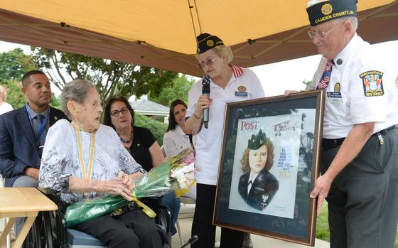 WWII Navy Veteran Joyce Edith Wagner Weaver receives a  painting of a picture of her when she enlisted in the Navy in 1942, during a celebration of her 100th birthday, in Pennsauken, N.J., July 9, 2022.