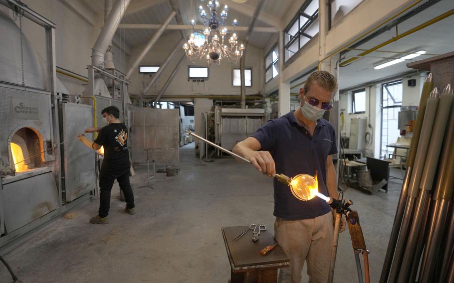 A glass-worker finishes a glass artistic creation in a factory in Murano island, Venice, Italy, Thursday, Oct. 7, 2021.