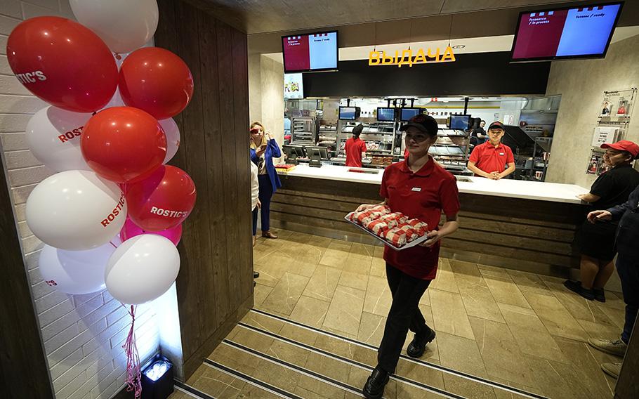 An employee of the Rostic’s restaurant in Tverskaya street carries food while celebrating opening ceremony in Moscow, Russia, on April 25, 2023. 