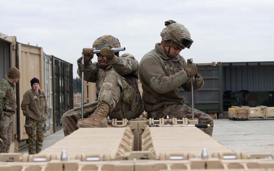 Two soldiers sit on top of equipment