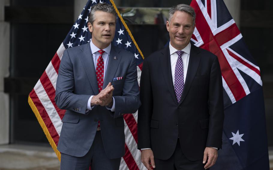 Pete Hegseth and Richard Marles standing together with the American and Australian flags behind them.
