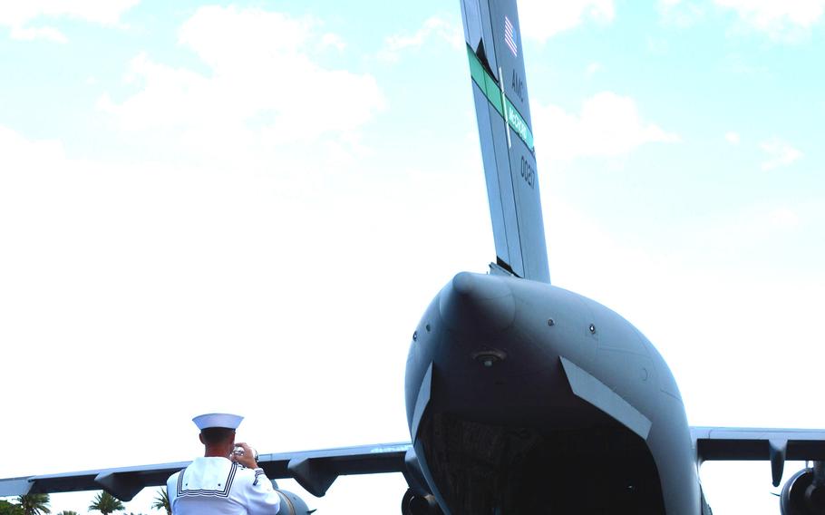 Petty Officer 1st Class Collin Reichow plays taps during an honorable carry ceremony for the remains of USS Oklahoma service members at Joint Base Pearl Harbor-Hickam, Hawaii, Thursday, June 24, 2021.