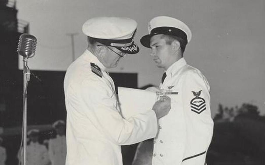 Dick Higgins (right) receives a medal for good conduct from a Navy commander at a naval air station in Lake City, Florida in 1944.