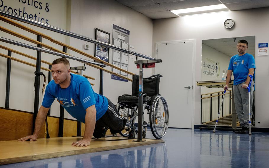 Aleksander Fedun, left, one of the Ukrainian soldiers getting replacement limbs at Medical Center Orthotics and Prosthetics in Silver Spring, Md., does a few push ups while working out with his new prosthetics. Watching at right is colleague Ruslan Tyshchenko. 