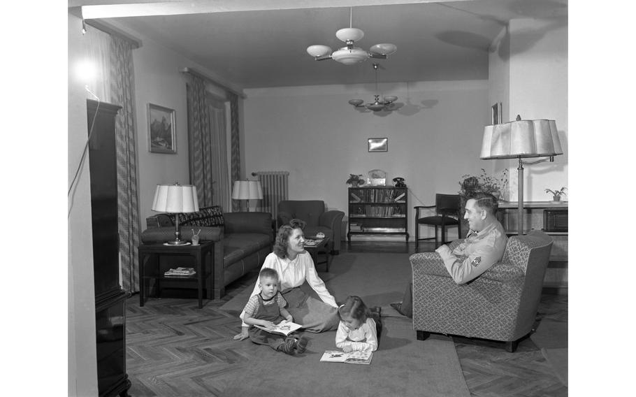 First Sgt. Thomas H. Fay, of H Co. 18th Inf., 1st Div., relaxes in his arm chair as his wife, Betty Jo reads with their two children, Colleen, 5, and Richard, 3, in the living room of their new apartment, one of the 156 newly constructed apartment units for service members and their family in Aschaffenburg, Germany.