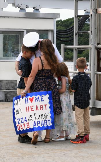 A sailor embraces his family
