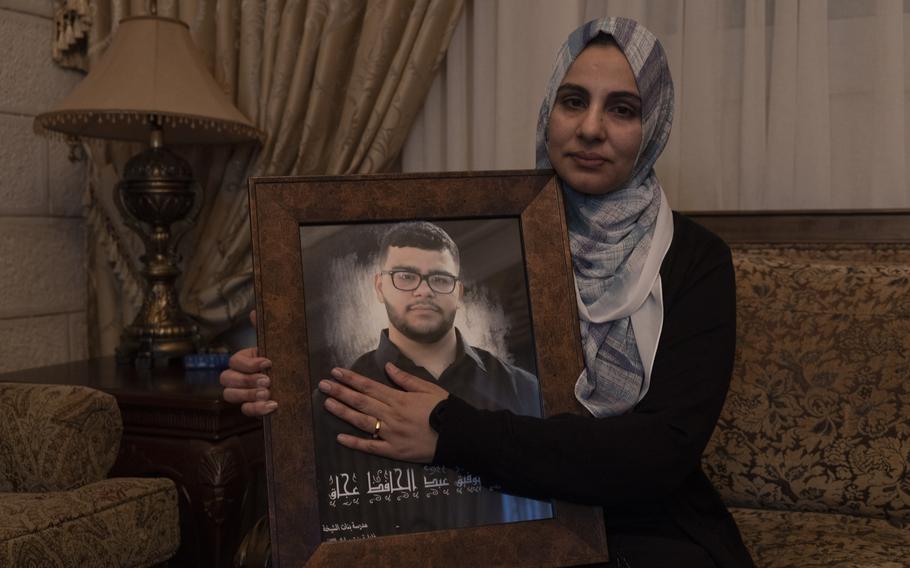 Mona Abdel Jabbar sits with a photograph of her late son, 17-year-old Tawfic Abdel Jabbar, at her home in the West Bank on Jan. 24, 2024. 