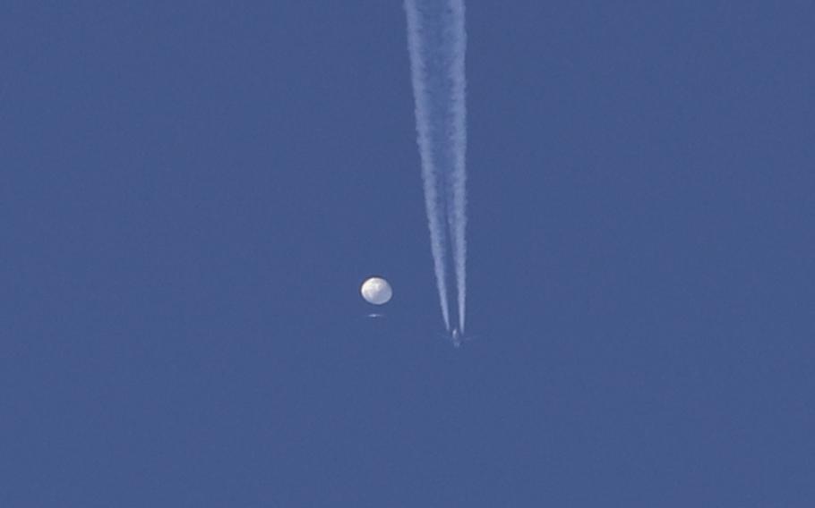 In this photo provided by Brian Branch, a large balloon drifts above the Kingstown, N.C. area, with an airplane and its contrail seen below it. 