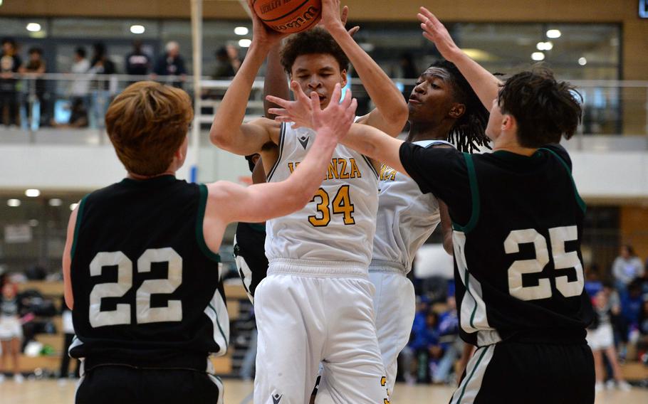 Vicenza’s Simon Gilbert pulls down a rebound in front of Naples’ Camden Kasparek, left, and Jettyn Jones in the boys Division II final at the DODEA-Europe basketball championships in Wiesbaden, Germany, Feb. 17, 2024. Vicenza won  the game 76-37.