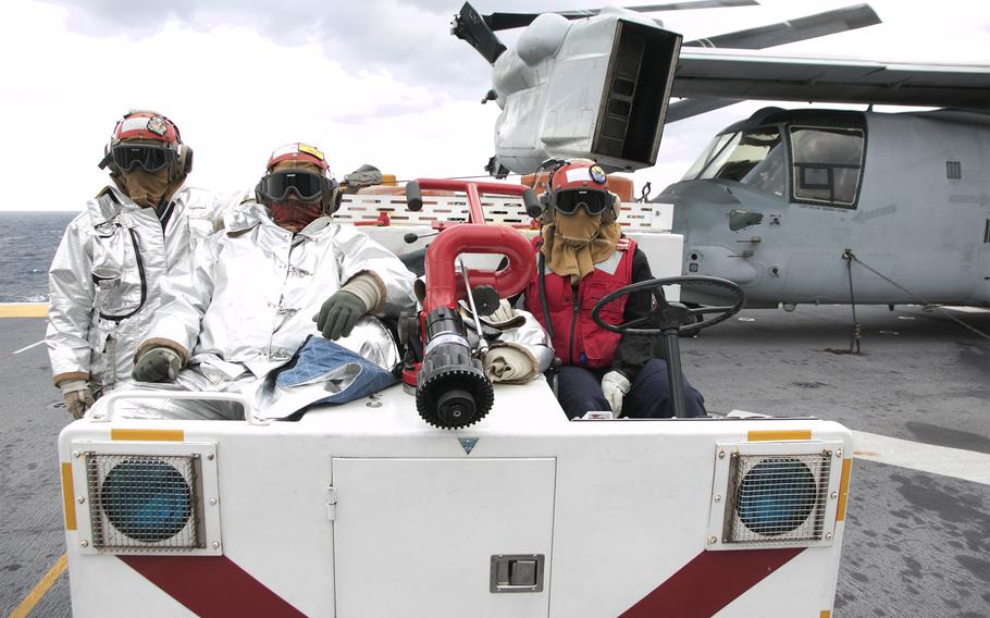 Navy firefighters aboard the amphibious assault ship USS America watch aircraft launch during the Noble Fusion exercise near Okinawa, Feb. 5, 2022.