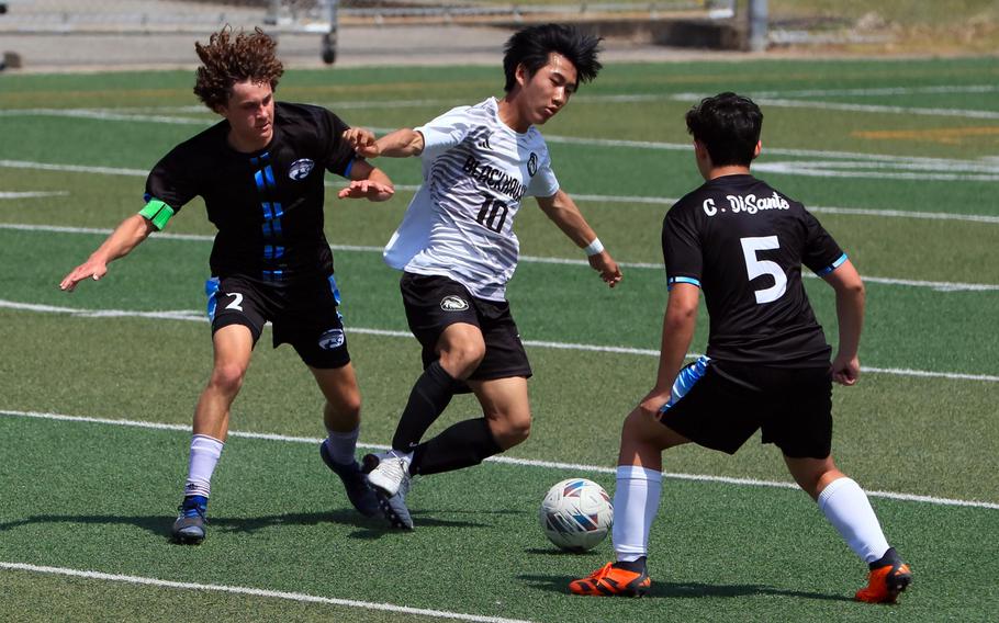 Humphreys’ Nathan Bahng tries to play the ball between Osan’s Reid Iverson and Cannon DiSanto during Saturday’s DODEA-Korea boys soccer match. The Blackhawks won 4-2.
