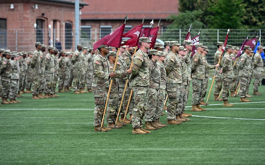 The side profiles of soldiers standing in formation on a grassy field.