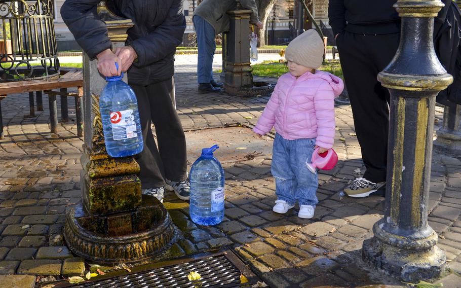 Liza, a child from Kyiv, Ukraine, waits to refill her toy watering can at a public fountain in Taras Shevchenko Park on Oct. 31, 2022. At least 50 residents flocked to the park to collect water, with some saying they were regulars at the pump and some saying they came due to a Russian missile attack that morning that left many homes and offices without water.