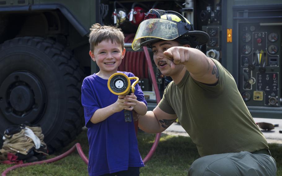 U.S. Marine Corps Cpl. Gabriel Soto, right, a native of California and an expeditionary firefighting and rescue specialist with Marine Wing Support Squadron (MWSS) 271, explains how to operate a firehose to a student during a career fair at Oaks Road Academy in New Bern, N.C., Friday, April 19, 2024. 