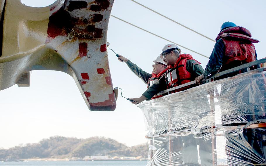 Capt. Daryle Cardone, commander of the USS Ronald Reagan, and Capt. Harry Evans III, executive officer, help paint one the carrier’s anchors gold at Yokosuka Naval Base, Japan, March 15, 2024.