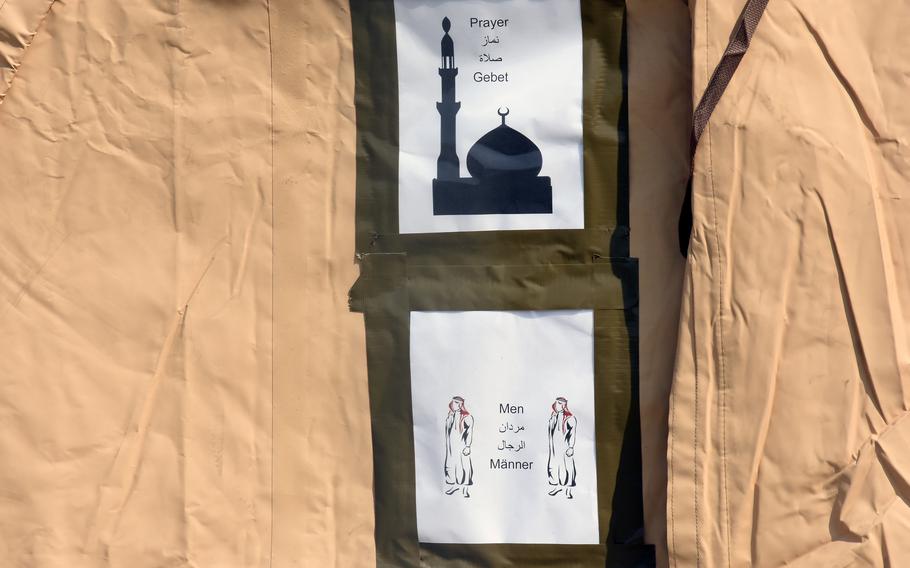 Signs show a tent for men to pray in at Ramstein Air Base, Germany, Aug. 21, 2021. Men and women have separate living quarters in the tents housing Afghan evacuees while they wait for transit to the United States.