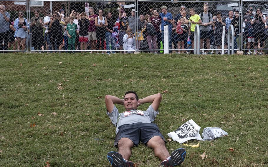 A runner relaxes as friends and family members of competitors wait outside the fence after the 48th Marine Corps Marathon on Sunday, Oct. 29, 2023, in Arlington, Va.