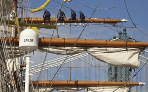 Sailors sit on a beam of the Mexican ship during repairs.