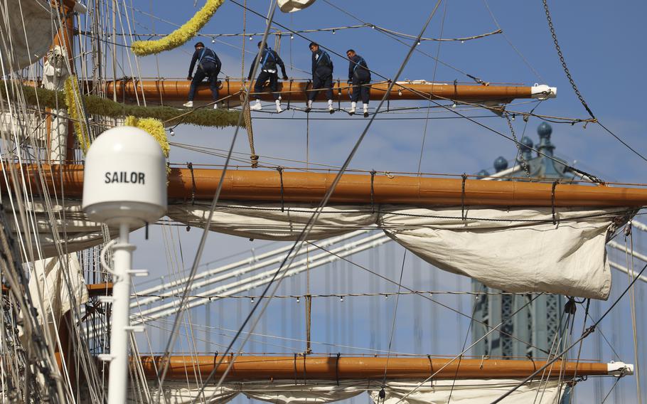 Sailors sit on a beam of the Mexican ship during repairs.