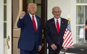 Trump raises his right hand and makes a fist, and Netanyahu stands next to him, smiling. An American flag is on the front of a car in front of them.