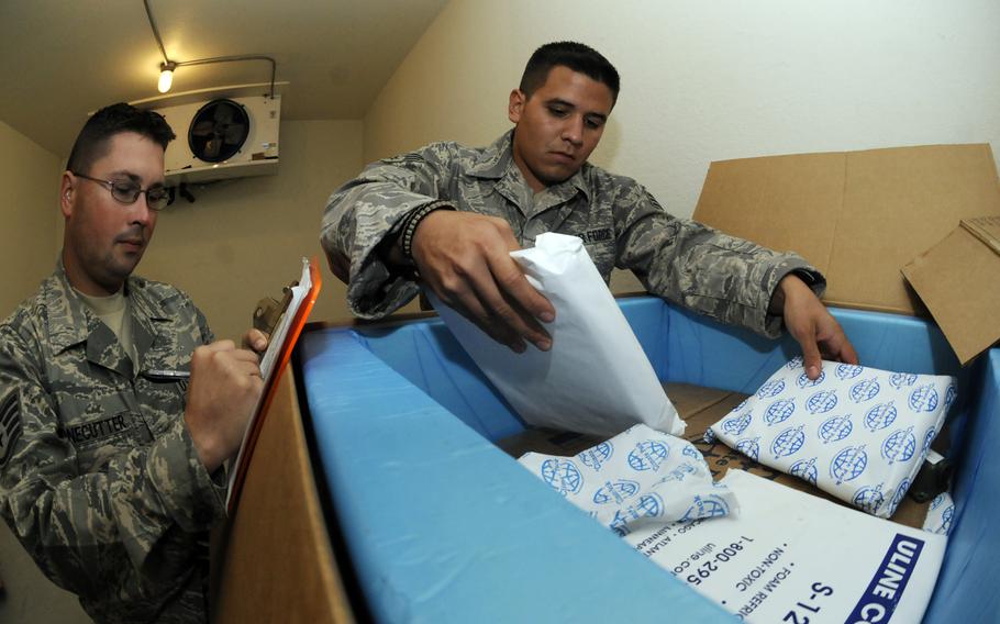 An airman stacks cold bricks on top of medical supplies, includng antivenom, while another logs the re-icing time at an undisclosed location in Southwest Asia in October 2008.