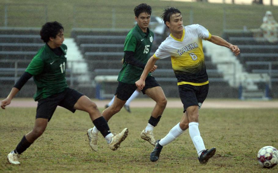 Kadena's Tuck Renquist dribbles through the rain ahead of Kubasaki's Aiden Oshana and Justin Murray during Wednesday's Okinawa boys soccer match. The Panthers won 3-2.