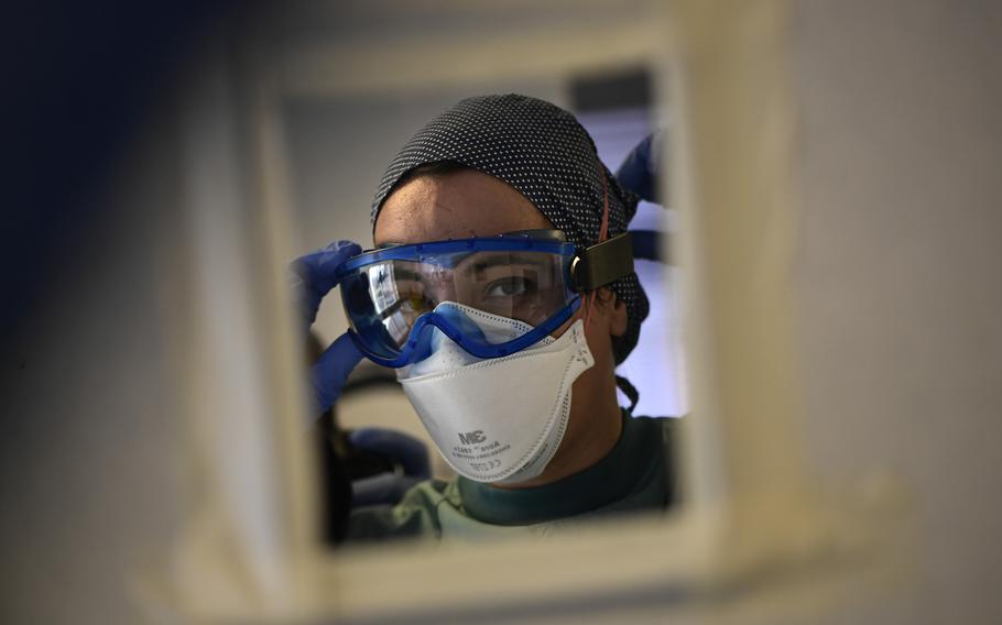A medical team member puts on personal protective equipment at a medical clinic in Pamplona, Spain, on Wednesday, Jan. 12, 2022.
