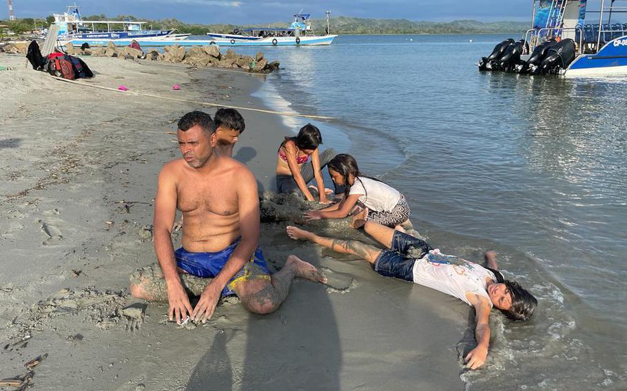 Venezuelan children relax on a beach in Necoclí, Colombia, with a man who has become a friend of the family on their journey. 