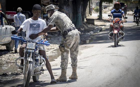 A Haitian Policeman frisks a motorcyclist at a check point on June 23, 2022, in Butte-Boyer 75, where a deadly gang war erupted in late April. Police launched a military style incursion to take back the key intersection. (Jose A. Iglesias/El Nuevo Herald/TNS)