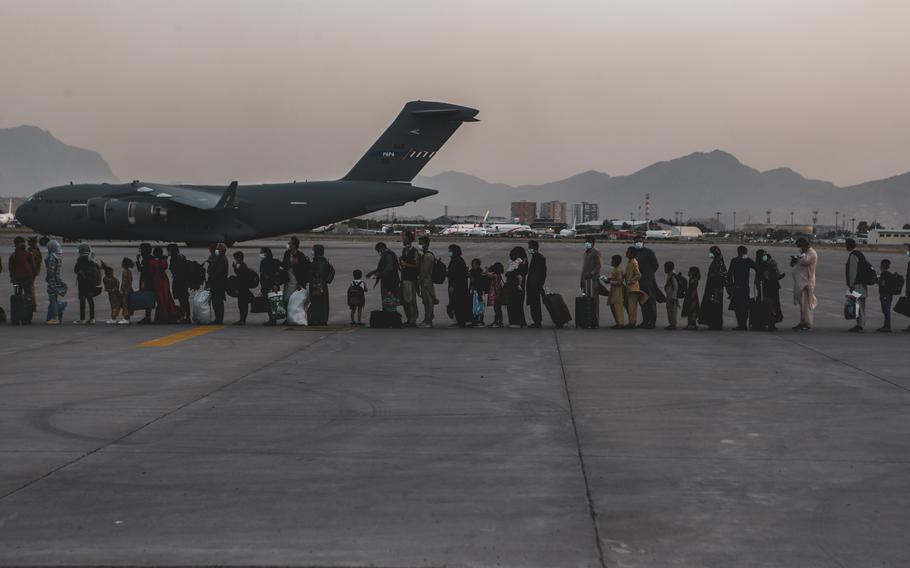 Evacuees wait to board a Boeing C-17 Globemaster III during an evacuation at Hamid Karzai International Airport, Kabul, Afghanistan, Aug. 23, 2021. The federal government’s review of the chaotic 2021 U.S. withdrawal from Afghanistan concludes the evacuation should have started sooner and faults former President Donald Trump for failing to pass on information and intelligence to President Joe Biden before he took office.