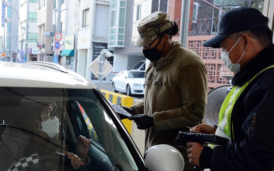 A soldier screens drivers before allowing them to enter Camp Walker in the coronavirus-hit city of Daegu, South Korea, Saturday, Feb. 22, 2020.