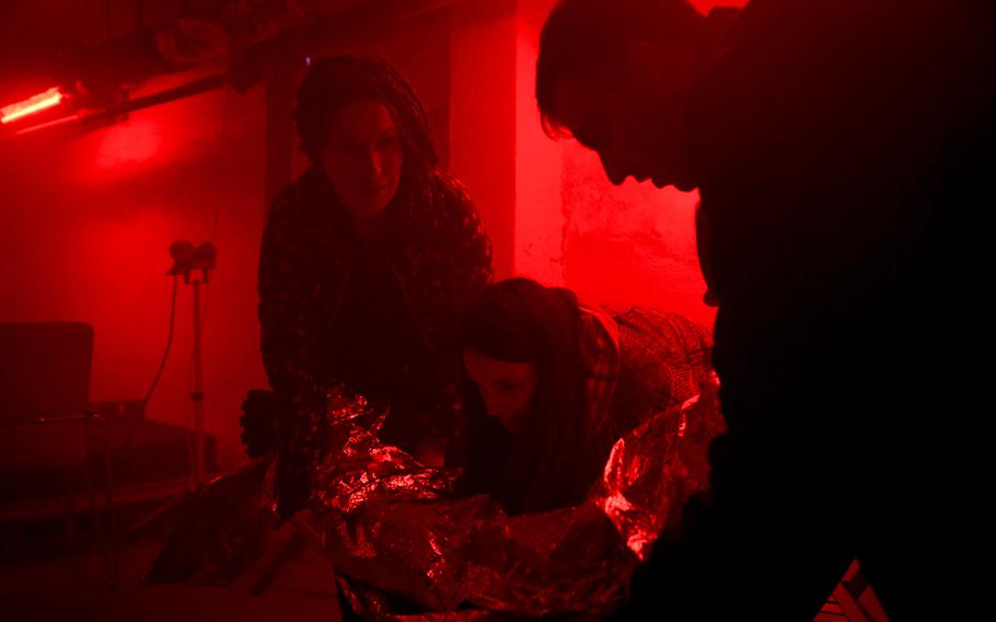 A Ukrainian woman prepares to lift a casualty and move him out of danger as part of first aid training for civilians, in a room designed to mimic the stresses of war in Kyiv, Ukraine, on Oct. 27, 2022.