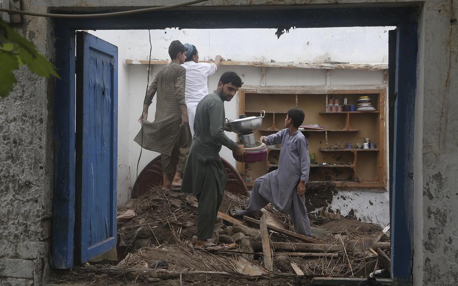 People salvage usable items from their house, after the roof collapsed due to heavy rains, in Peshawar, Pakistan, Thursday, July 28, 2022. The National Disaster Management Authority said Wednesday that 337 people died across the country in rain-related incidents. 