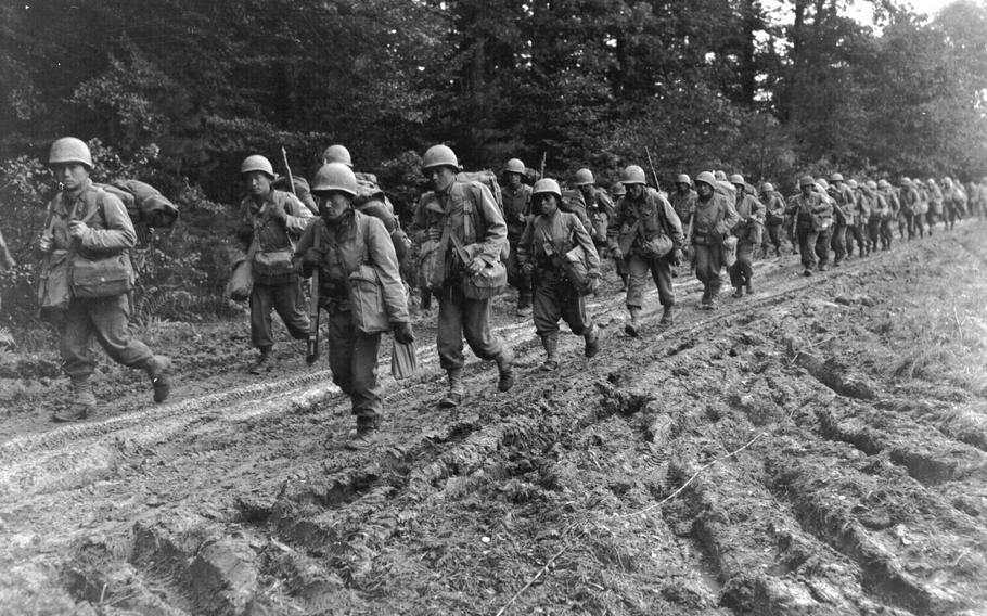 Japanese-American infantrymen of the 442nd Regimental Combat Team hike up a muddy French road in the Chambois Sector, France, in late 1944.